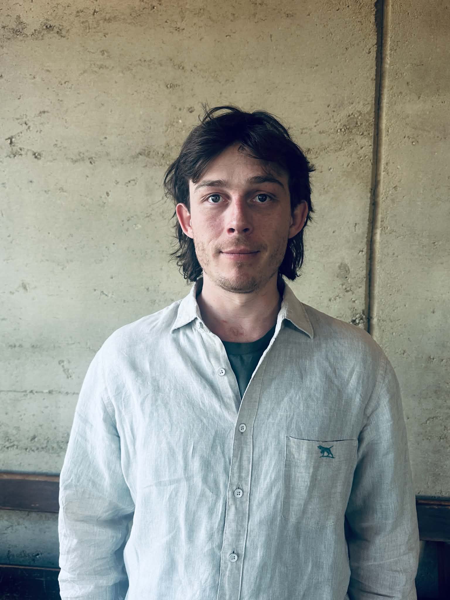 AJ Dryden, who runs iTile, standing against a rammed-earth wall