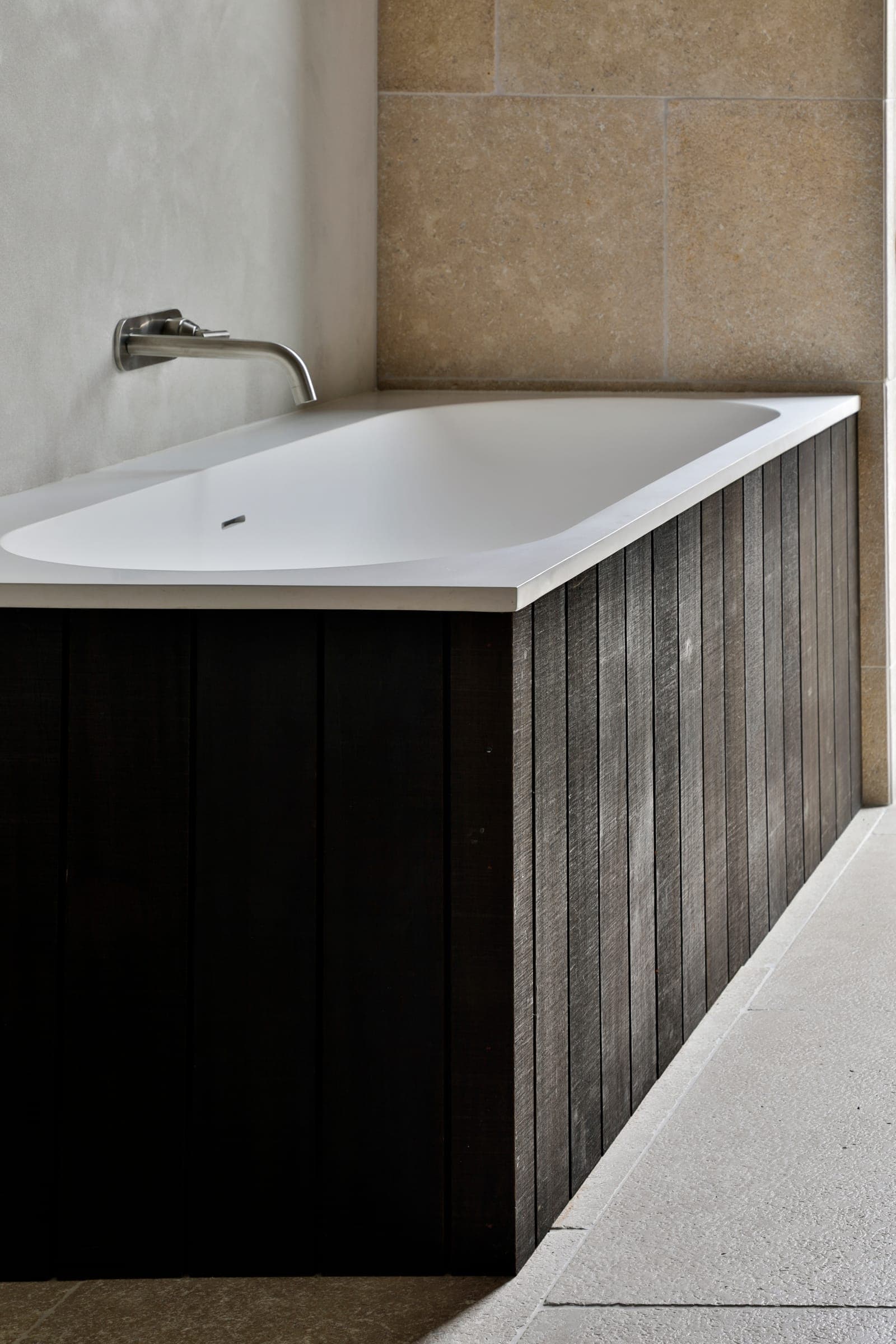 Stone bath panel meeting the limestone wall at a clean joint