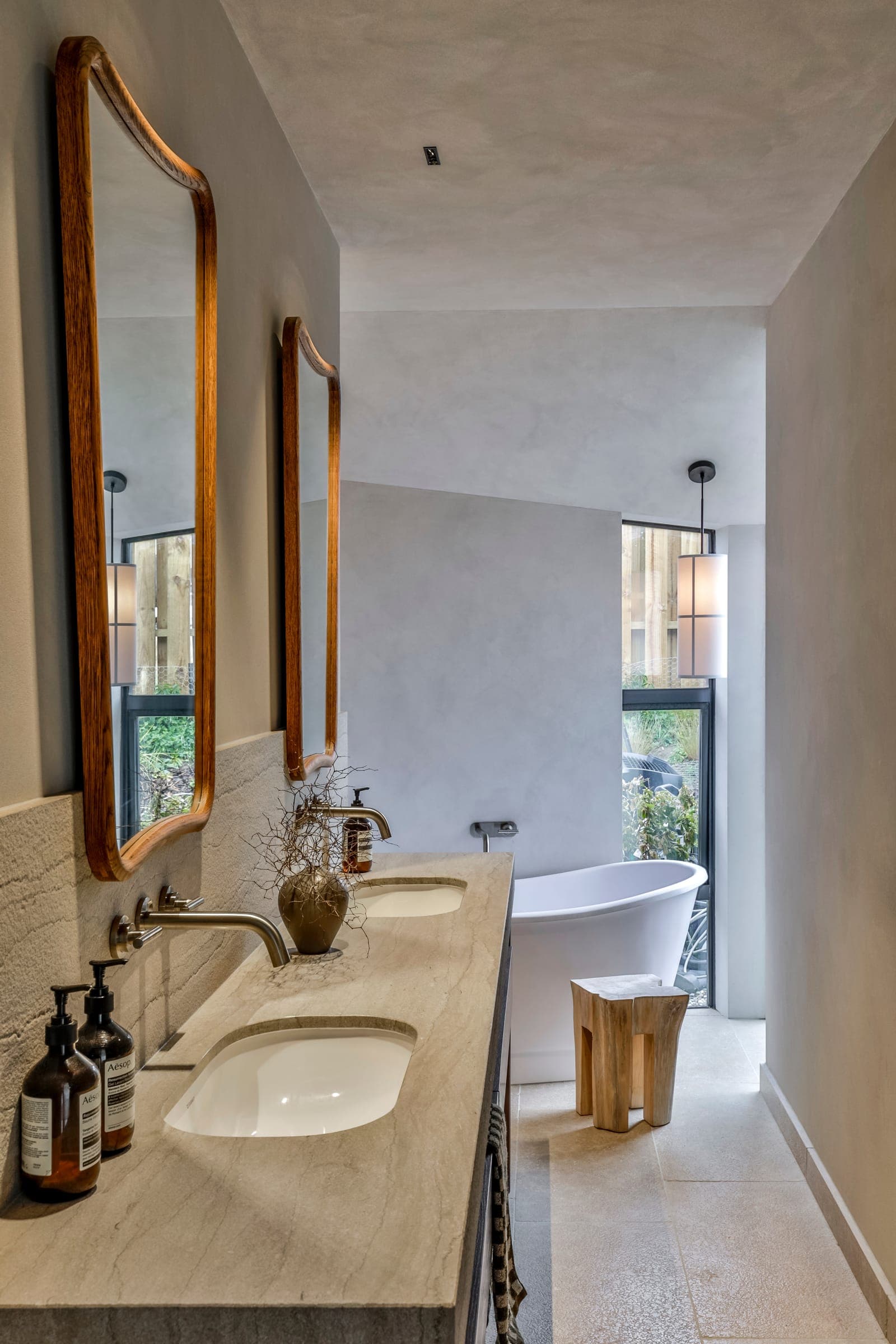 Limestone ensuite: stone vanity wall running through to a freestanding bath