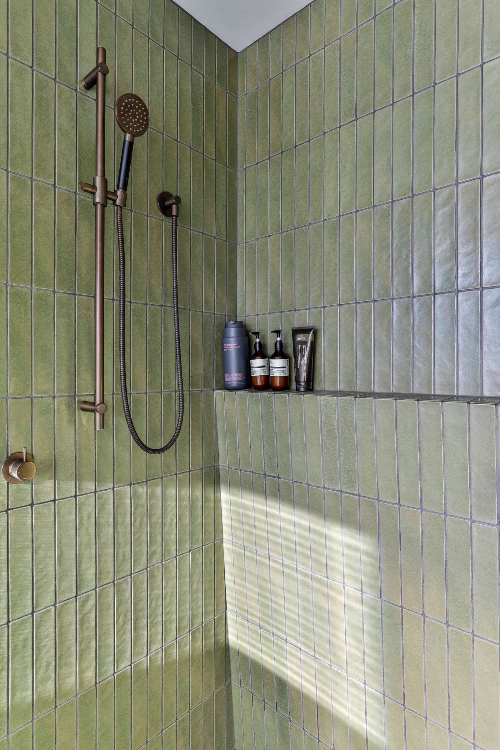 Handmade green tile in vertical stack bond inside the shower