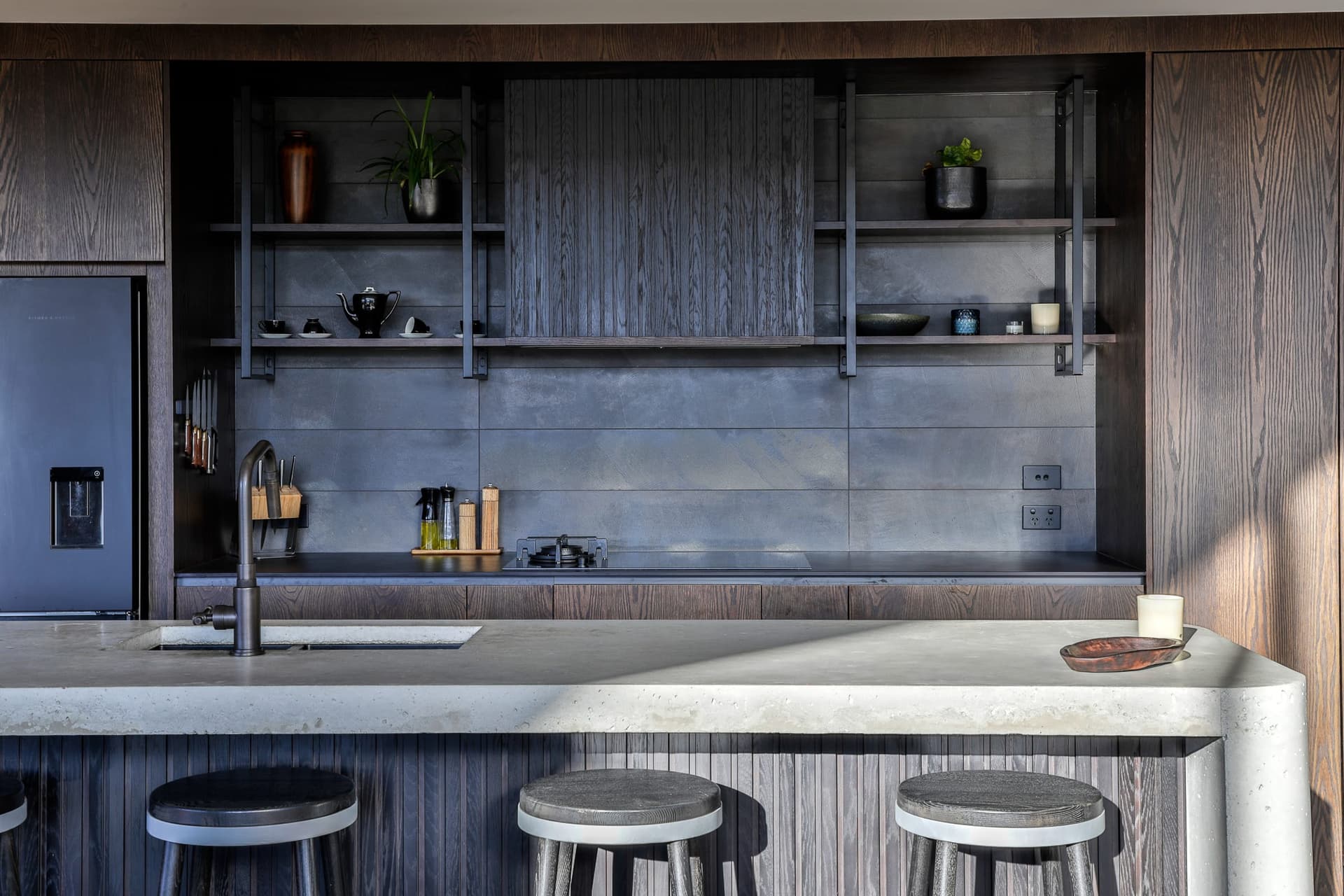 Kitchen with a dark tiled splashback in an off-form concrete house