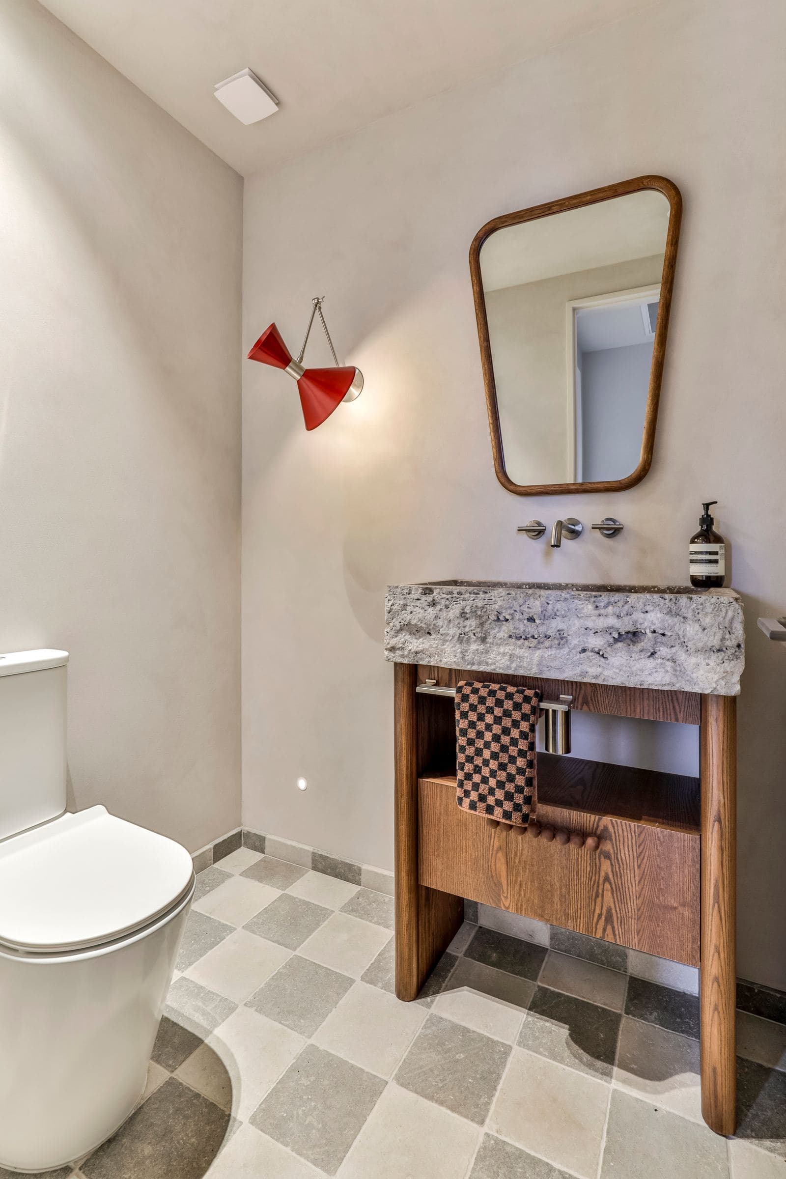 Powder room with a checkerboard tumbled stone floor and a stone basin on a timber stand